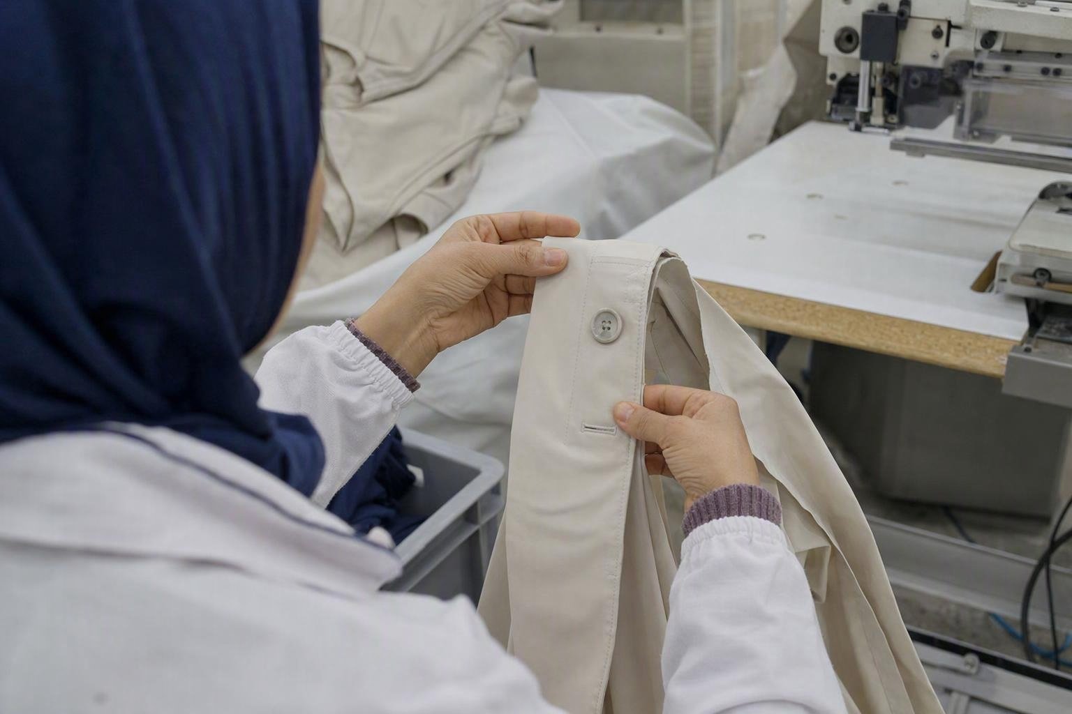 Contrôle rapproché d’une boutonnière industrielle, de son ouverture et de l’alignement du bouton sur une patte de vêtement.